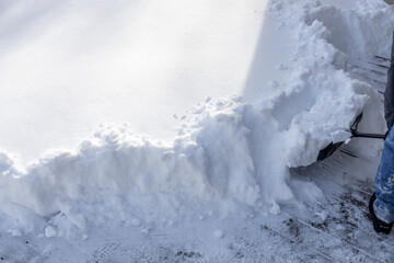 Partial view of an unrecognizable adult shoveling deep snow following a blizzard