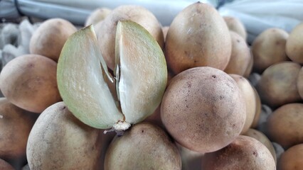 Close-Up of Fresh Sapodilla Fruit with One Cut Open in Market Display Indonesia