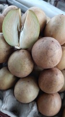 Close-Up of Fresh Sapodilla Fruit with One Cut Open in Market Display Indonesia