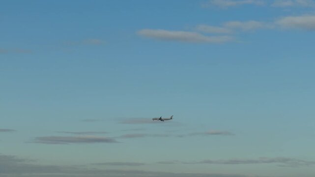 Passenger airplane flying across a clear blue sky with white clouds
