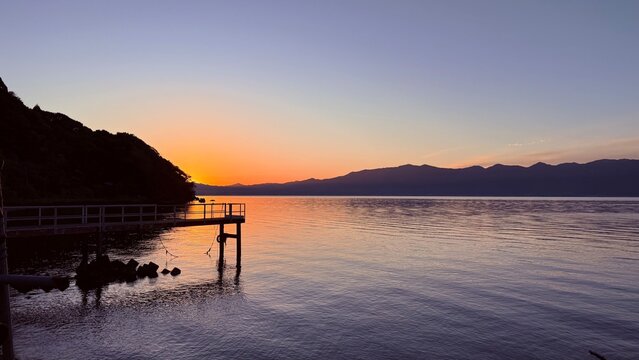 ilhouetted pier stretching into the calm water of Lake Biwa at sunset