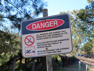 Danger sign near the Nogoa River with trees in the background in Emerald, Queensland, Australia