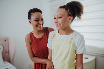 Obraz premium Happy African American mother and teenage daughter laughing together at home