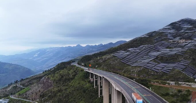 aerial video of the Shanghai&ndash;Kunming Expressway winding through mountainous solar farms, showcasing clean energy and transport infrastructure at early morning, Guizhou, China