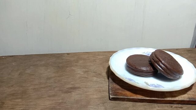 Static shot of hands serving chocolate marshmallow pies on a rustic wooden table.