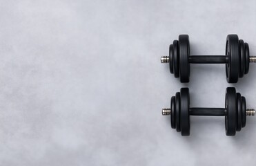 Two adjustable black dumbbells resting on a concrete gray surface, providing ample copy space for fitness or workout concepts