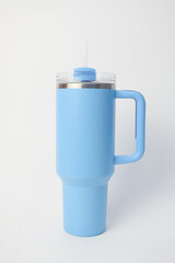 Large light blue insulated tumbler with handle and straw. Modern stainless steel travel mug for cold or hot drinks isolated on white background
