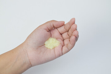 Close up of yellow cosmetic gel or lotion on a human palm, isolated on white background