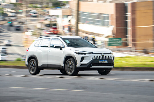 White Toyota Corolla Cross SUV front panning shot, Japanese family car driving in city