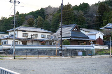 広い敷地に建つ立派な日本家屋と火の見櫓・石垣と塀に囲まれた伝統的な農家の風景・田舎の夕暮れ時の静寂と日本の原風景 © taka