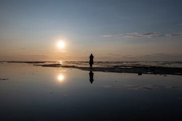 A Peruvian Woman Takes Photos with a Camera and Strolls through Baie Sainte-Claire at the Sunset, in Anticosti, Quebec, Canada