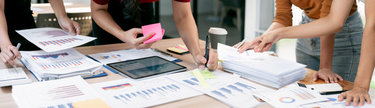 Collaborative business team analyzing financial data charts and statistics on office desk during a productive meeting.