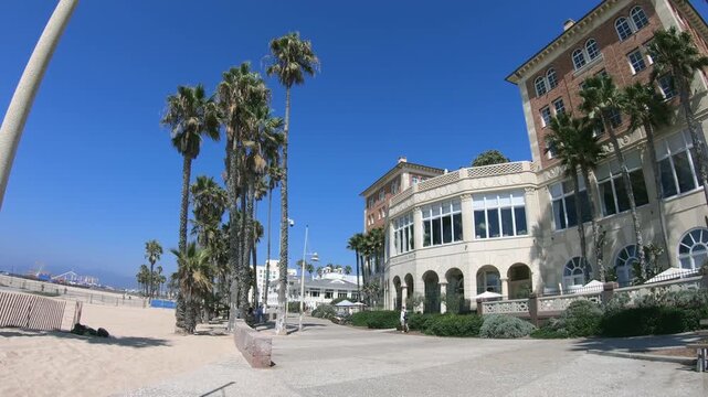 Tourist POV walking down the beach walk under the pam trees during summer vacation on the west coast, sunny summer spirit in Venice Beach, California