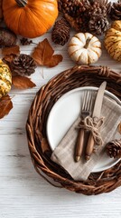 Autumnal place setting with pumpkins, pinecones, and fall leaves on a white wooden table
