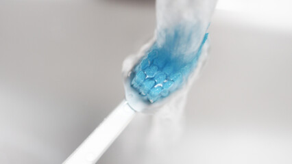 Brushing teeth with water running from faucet