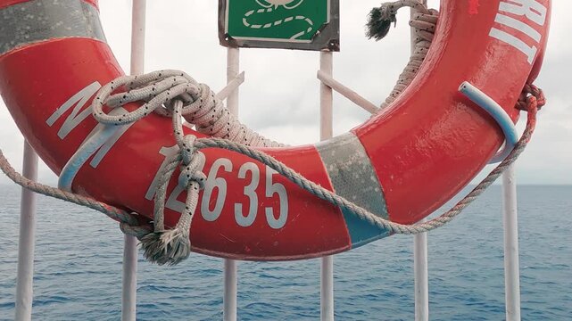 Plastic orange saving belt by the railing fence of the ferry sailing on sea;