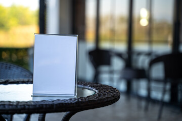 Minimal blank table sign mockup in cafe interior, selective focus and soft light. Perfect for menu design, restaurant promotion and marketing message.