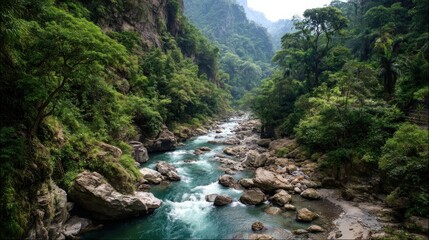 Lush, green mountain valley with a flowing turquoise river over rocks & boulders, forest covers the steep mountainsides