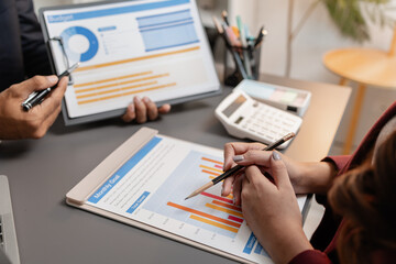 A collaborative startup meeting showing professionals reviewing financial charts and discussing strategic ideas in a modern office setting.