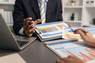A collaborative startup meeting showing professionals reviewing financial charts and discussing strategic ideas in a modern office setting.