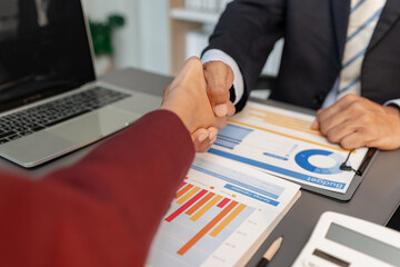 A business meeting scene where professionals review financial charts and exchange insights, highlighting strategic planning and collaborative decision making in a modern office environment.