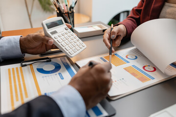 A business meeting scene where professionals review financial charts and exchange insights, highlighting strategic planning and collaborative decision making in a modern office environment.