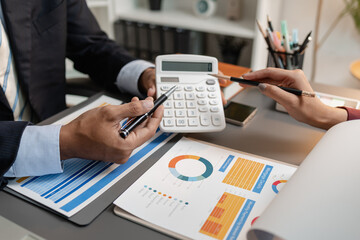 A business meeting scene where professionals review financial charts and exchange insights, highlighting strategic planning and collaborative decision making in a modern office environment.