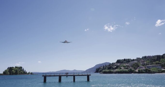 Amazing cinematic view of large passenger airplane flying overgead and landing at Kerkyra Airport, Corfy island, Greece in slow motion