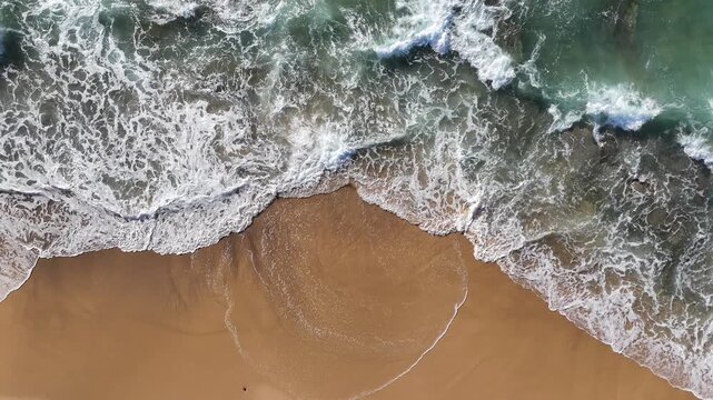 Top down aerial view waves lapping the shore at Dudley Beach - NSW Australia