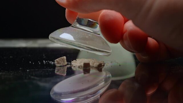 Drug dealer crushing prescription opioid drug to mix with fentanyl. Synthetic opioids and fentanyl crisis. On the streets it is injected, snorted sniffed, smoked, taken orally by pill or tablet.