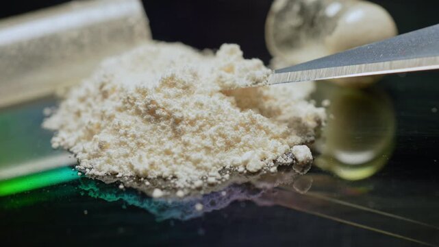 Lethal dose of fentanyl on the tip of craft knife blade. Two milligrams of fentanyl is lethal dose for humans. Tiny pile of powder to give a sense of scale. Synthetic narcotic analgesic drug.