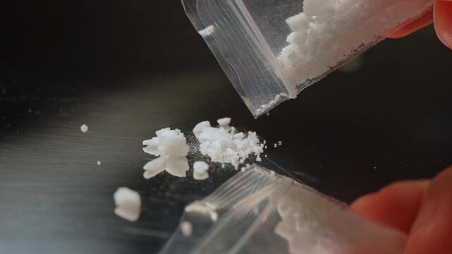 Synthetic opioids crystals like fentanyl or nitazenes drugs pour from the plastic bag. Opioids account for two thirds of drug overdose deaths worldwide. Extremely potent drugs.