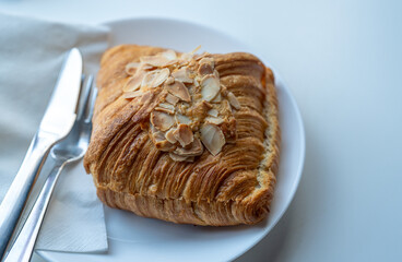 A delicious almond croissant is served on a white plate.