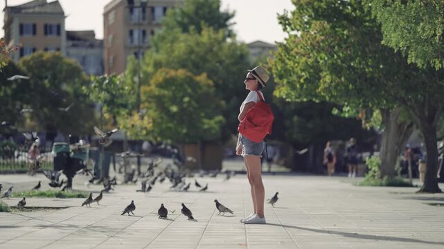 Woman feeds flock of pigeons in a city of Kelkira, a capital of Corfu island in Greece, slow motion