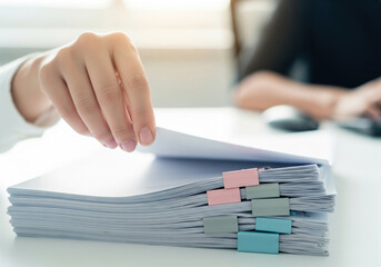Office worker reviewing stack of documents with colorful binder clips