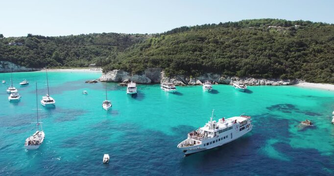 Tropical paradise turquoise tranquil sandy beach of Mesovrika with sail boats docked in island of Antipaxos, Ionian, Greece