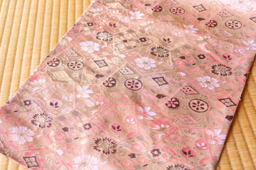 畳の上に置いたピンクのかわいい着物の帯、クローズアップ