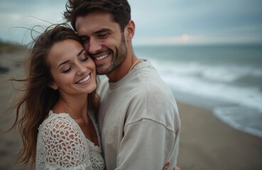 Obraz premium Smiling couple embrace tightly on sandy beach. Woman and man laugh, feel joy. Gentle waves wash shore, ocean water sparkles. Romantic scene shows true connection, deep affection.