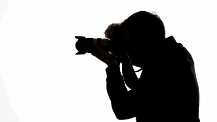 Silhouette of a photographer holding a professional camera and taking a picture.