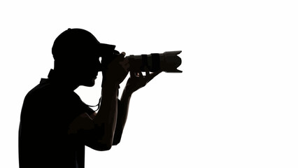 Silhouette of a photographer holding a professional camera and lens.