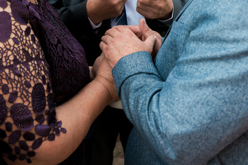 Fototapeta premium Close-up of family hands joined during a wedding ceremony, symbolizing love, unity, support, and emotional connection at a meaningful celebration.
