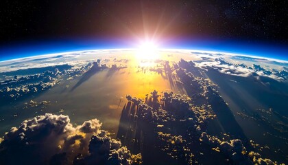 Aerial view of Earth at dawn, with the sun rising above a layer of clouds, illuminating the atmosphere