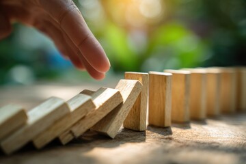 Hand pushing domino, triggering a chain reaction