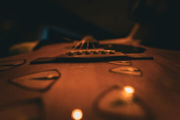 Close-up view of acoustic guitar bridge and strings with shallow depth of field, warm cinematic...