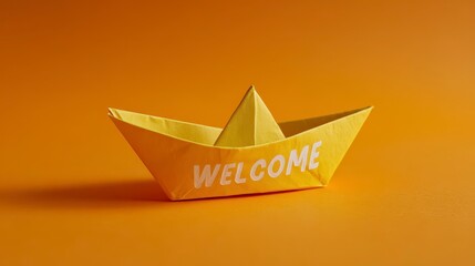 A brightly colored origami boat with "WELCOME" emblazoned on the side sits on an orange backdrop. The boat features a sharp triangular sail