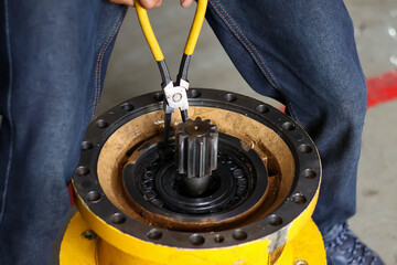 Technician using yellow-handled snap ring pliers to precisely install a retaining ring on a heavy...