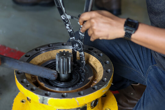 Technician using snap ring pliers to install or remove a circlip on a heavy industrial yellow metal gear component.