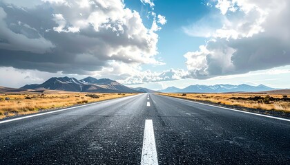 A long, empty road stretches toward distant mountains under a vibrant blue sky filled with clouds