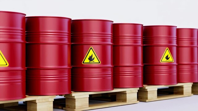 Red metal barrels with warning symbols on wooden pallets arranged in a row against a white backdrop