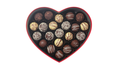 Heart shaped container filled with round chocolates in various colors and textures, arranged closely together on white and transparent
